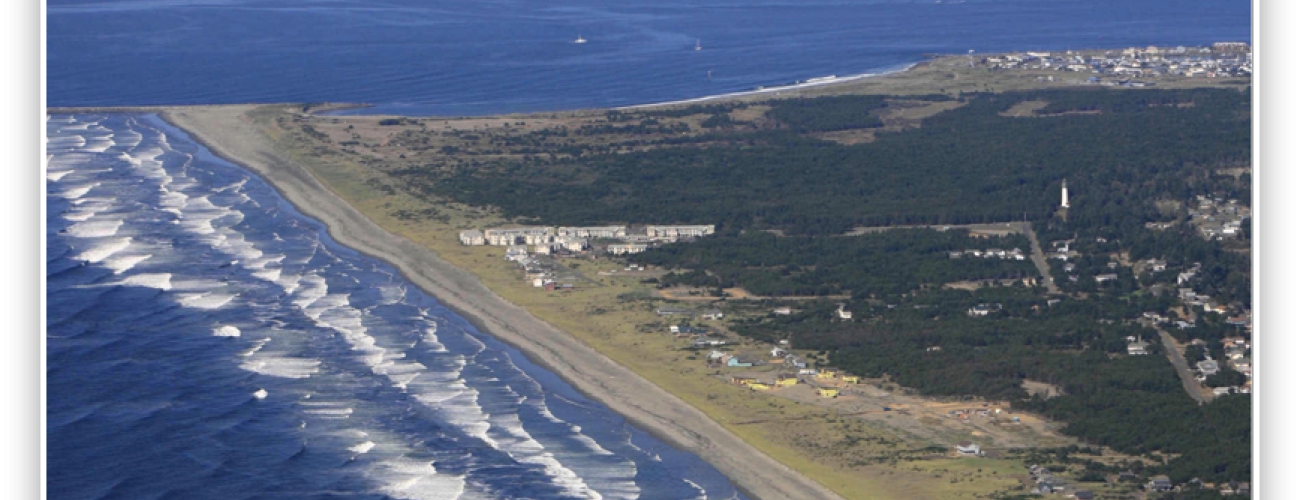 Aerial view of the Westport Light Park point. Left is the ocean with white cape waves. Right is the beach, and trees and some buildings right of that.