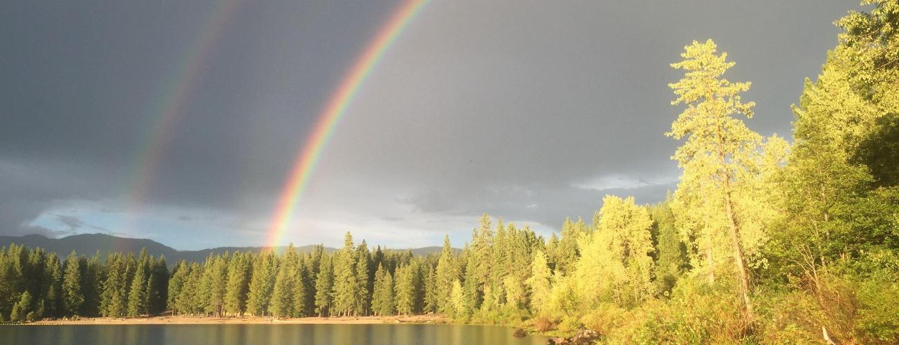 A double rainbow over a lake with cloudy skies