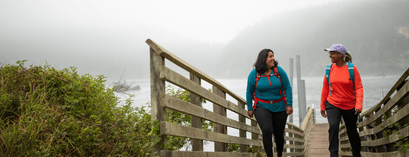 Two people walk along boardwalk at Deception Pass