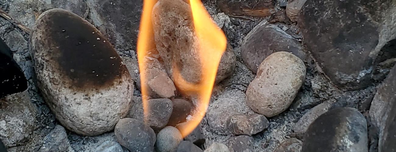 dancing flame rising from pebbles on the ground