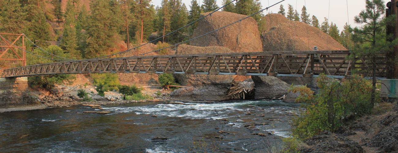 suspension bridge over river surrounded by rocky cliffs