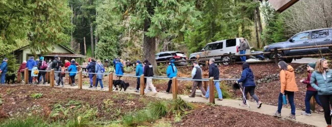 Group of people hiking along trail with cars park in background