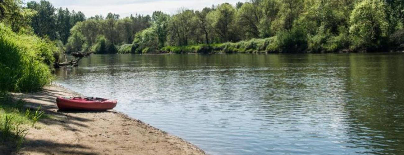 sand beach beside river with kayak resting on beach