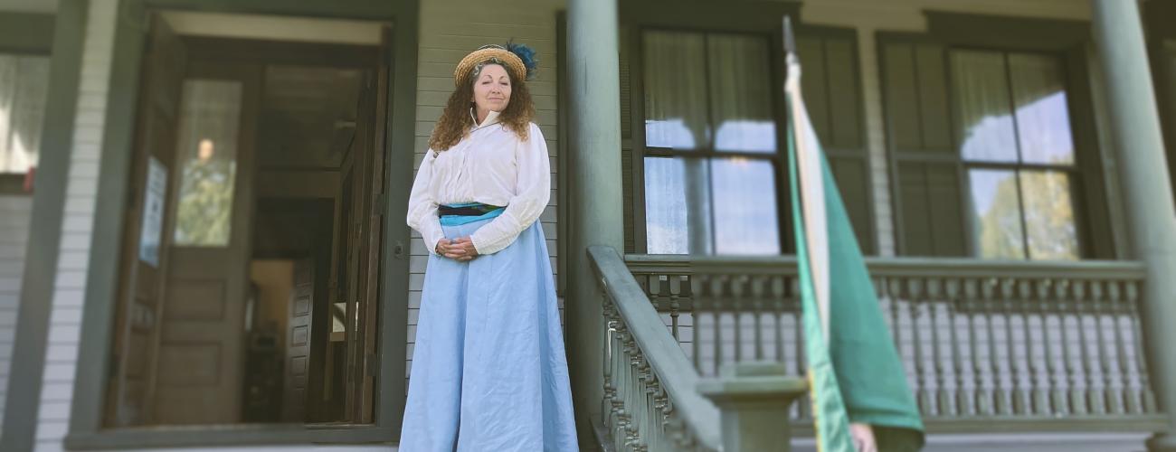 Volunteer dressed in Edwardian style clothing on the porch of the Commanding Officer's Quarters Museum