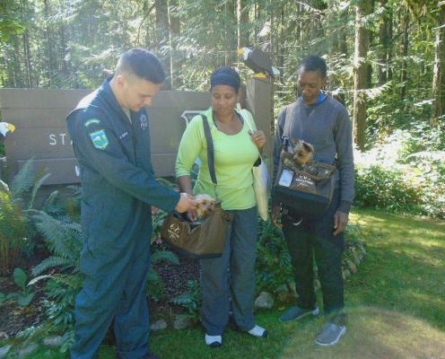 A ranger and two people with matching small dogs in matching purses