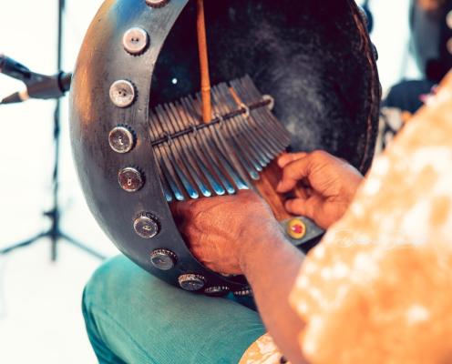 A closeup of a traditional instrument from Africa with a musician's hands playing it.