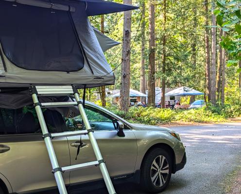 A rooftop tent on a Subaru Outback, with a ladder to the tent.