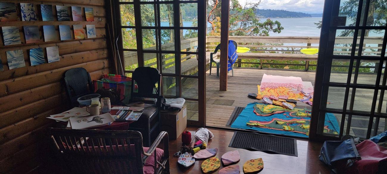 View from inside the Artist in Residence cabin out onto the back porch. Artwork is laid out.