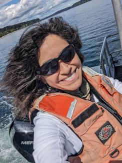 Blog author, woman with salt and pepper hair and white shirt in boat with life jacket and sunglasses