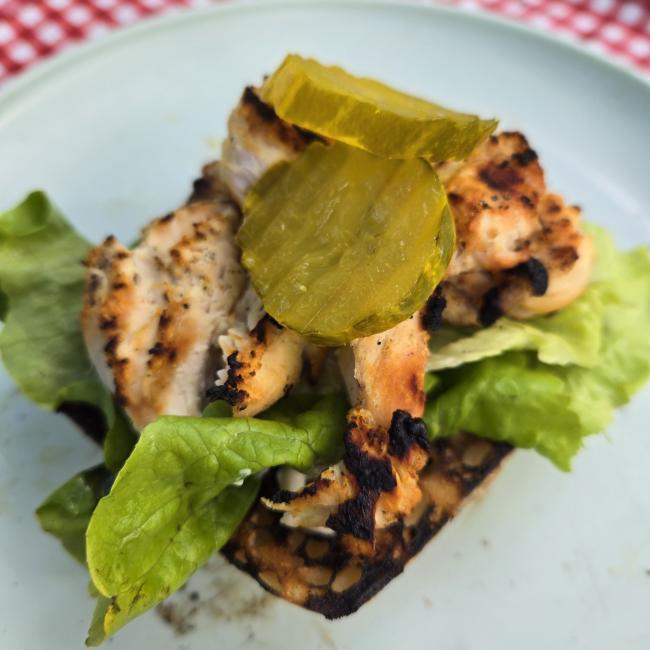 Chicken sandwich on a blue plate and checkered table cloth