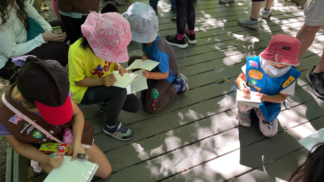 Girl Scouts circled up taking notes while they learn from our interpretive rangers