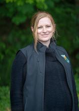 Washington State Parks Communications Director Clare DeLong-Tuminez poses in front of evergreen trees.