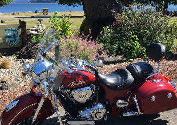 Motorcycle parked in front of a small grassy area and a lake