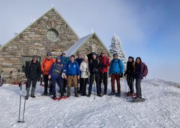 Group of Snowshoers standing in front of a snow covered stone cabin