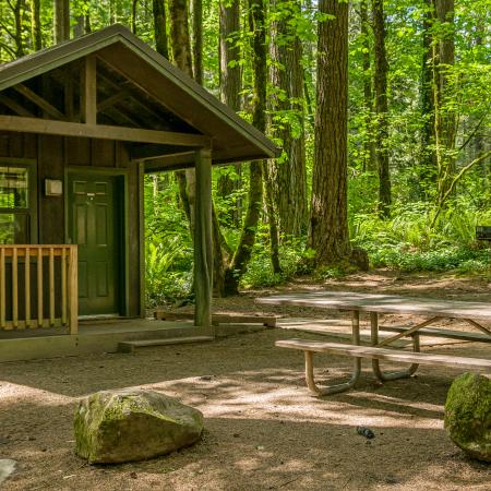 A cabin at Battle Ground Lake State Park with picnic tables out front.