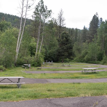 Paved RV campsite with electricity pedestal on semi-level ground surrounded by grass