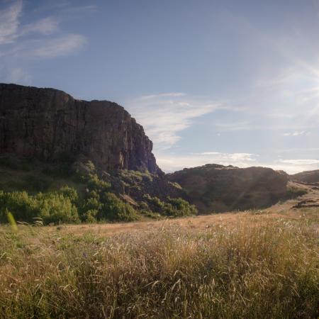 large outcrop of rocks and a bluff in a grassy meadow with blue skies