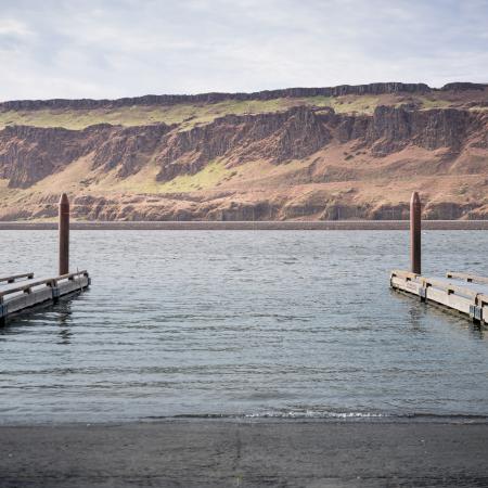 Two docks on water facing high golden hills