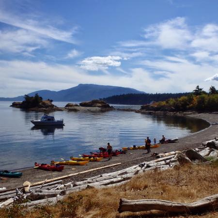 island shoreline kayaks parked on shore with boat in the cove moored