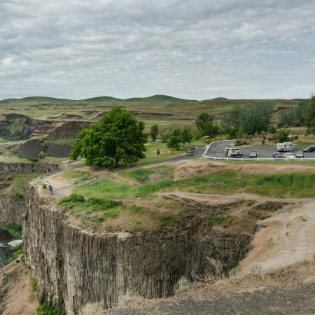 A parking lot with a short trail to an overlook at the edge of a canyon. A river is flowing below.