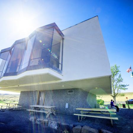 Outside view of the Interpretive Center, sitting on a river rock foundation with a large white structure on top with large glass windows.