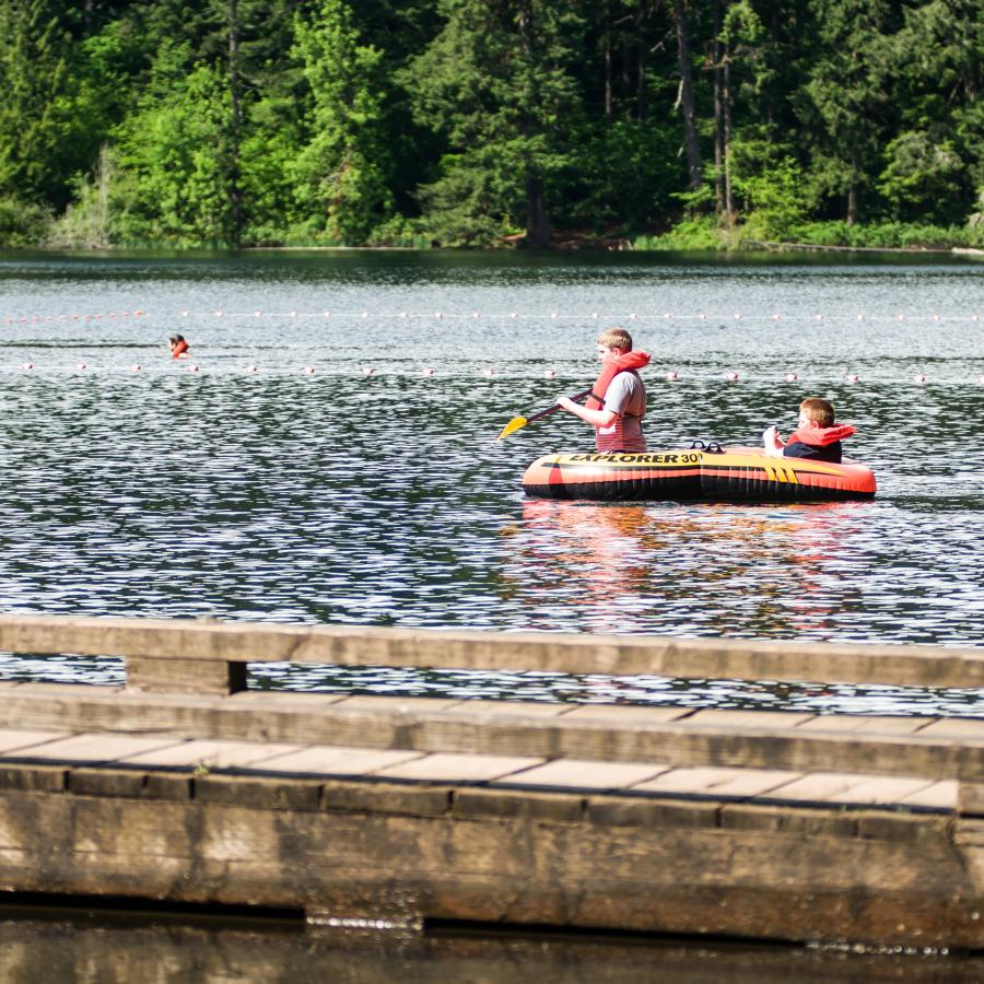 Children floating, rafting, and swimming on Battle Ground Lake on a sunny day.