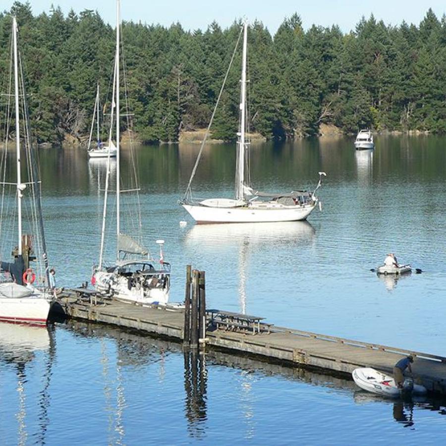 blue peaceful waters at boat dock reaching out into the water with boats moored to it