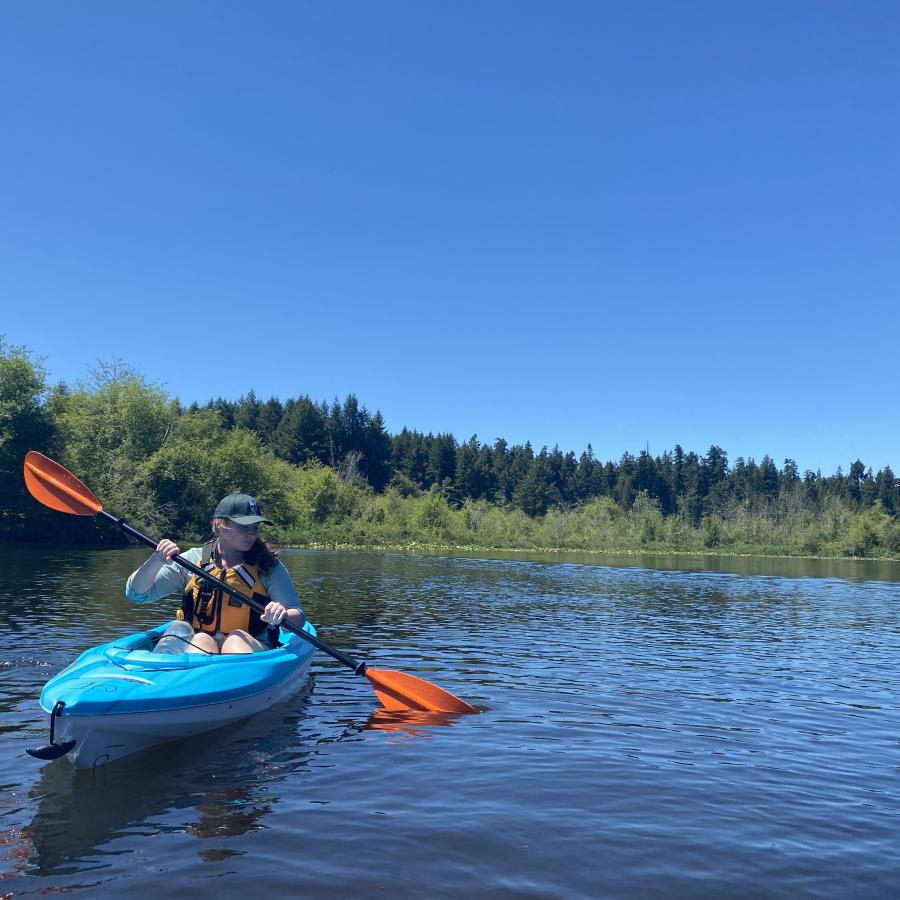 Woman Kayaking on a lake while wearing a life jacket.