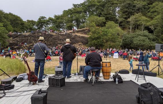 A view of the audience from behind a band on stage at Waikiki beach during a summer concert. 