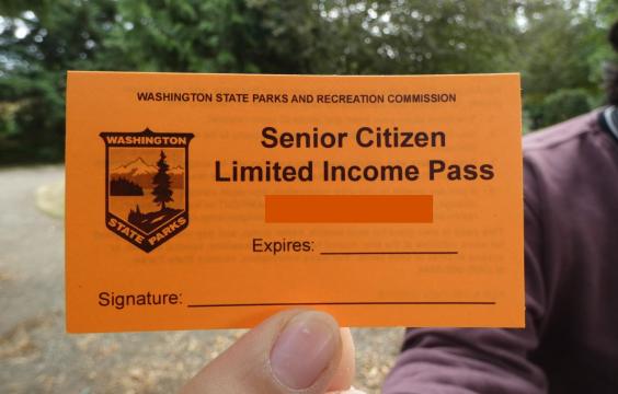 Hand holding a orange Senior Limited Income pass.